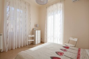 A bedroom with a bed, a desk, a chair, and curtains.