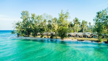 A beachfront resort with multiple bungalow-style accommodations, a sandy beach, and clear turquoise waters.