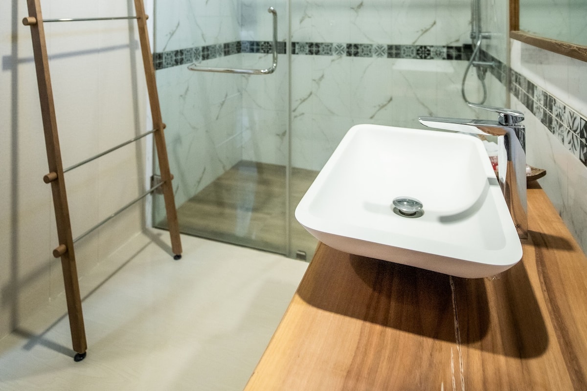 A modern bathroom with a glass shower enclosure, a wooden vanity, and a large mirror.