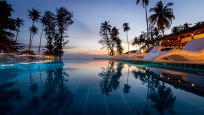 A serene infinity pool with clear water reflecting palm trees and a sunset sky. - Seacret Kohkood Resort (Ko Kood)