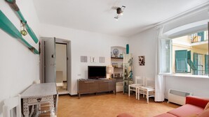 A living room with a television, a sofa, a table, and a chair. - Apartment 'Oceane Paradise- Charlot' with Sea View, Balcony and Wi-Fi (Levanto)