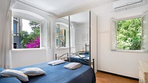 A bedroom with a bed, a dresser, a window with a view of trees, and a mirror. - Apartment 'Oceane Paradise- Charlot' with Sea View, Balcony and Wi-Fi (Levanto)