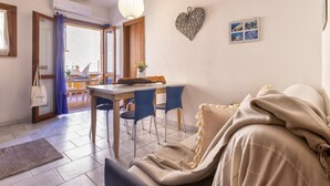Un salón acogedor con un sofá, una mesa de comedor y sillas. Hay una decoración con forma de corazón en la pared y un pequeño marco de fotos.