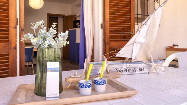 Una mesa de madera con un florero decorativo, dos tazas de cerámica con motivos florales y una maqueta de un velero.