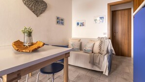 Una habitación acogedora con una mesa de madera, una silla azul, un sofá con cojines estampados y una decoración de corazón en la pared.