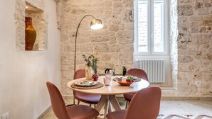 Un comedor con pared de piedra, una mesa redonda y sillas rojas.