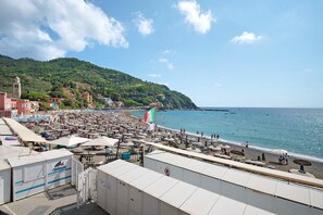 A coastal area with a beach, a hill with buildings, and a flag. - Apartment 'Oceane Paradise - Luigi 14' with Sea View, Balcony and Wi-Fi (Levanto)