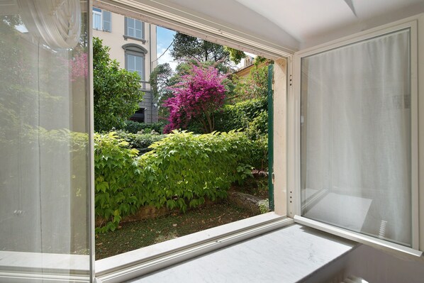 A window with a view of a garden, a building in the background, and a door frame. - Apartment 'Oceane Paradise - Luigi 14' with Sea View, Balcony and Wi-Fi (Levanto)