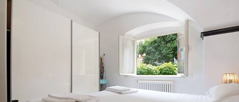 A bedroom with a bed, a window, and a radiator.