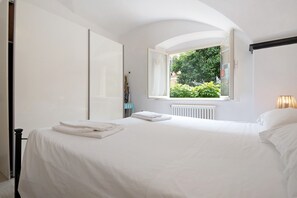 A bedroom with a bed, a window, and a radiator.