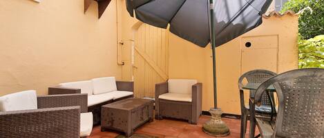 A patio with wicker furniture, a table, chairs, and a large umbrella.