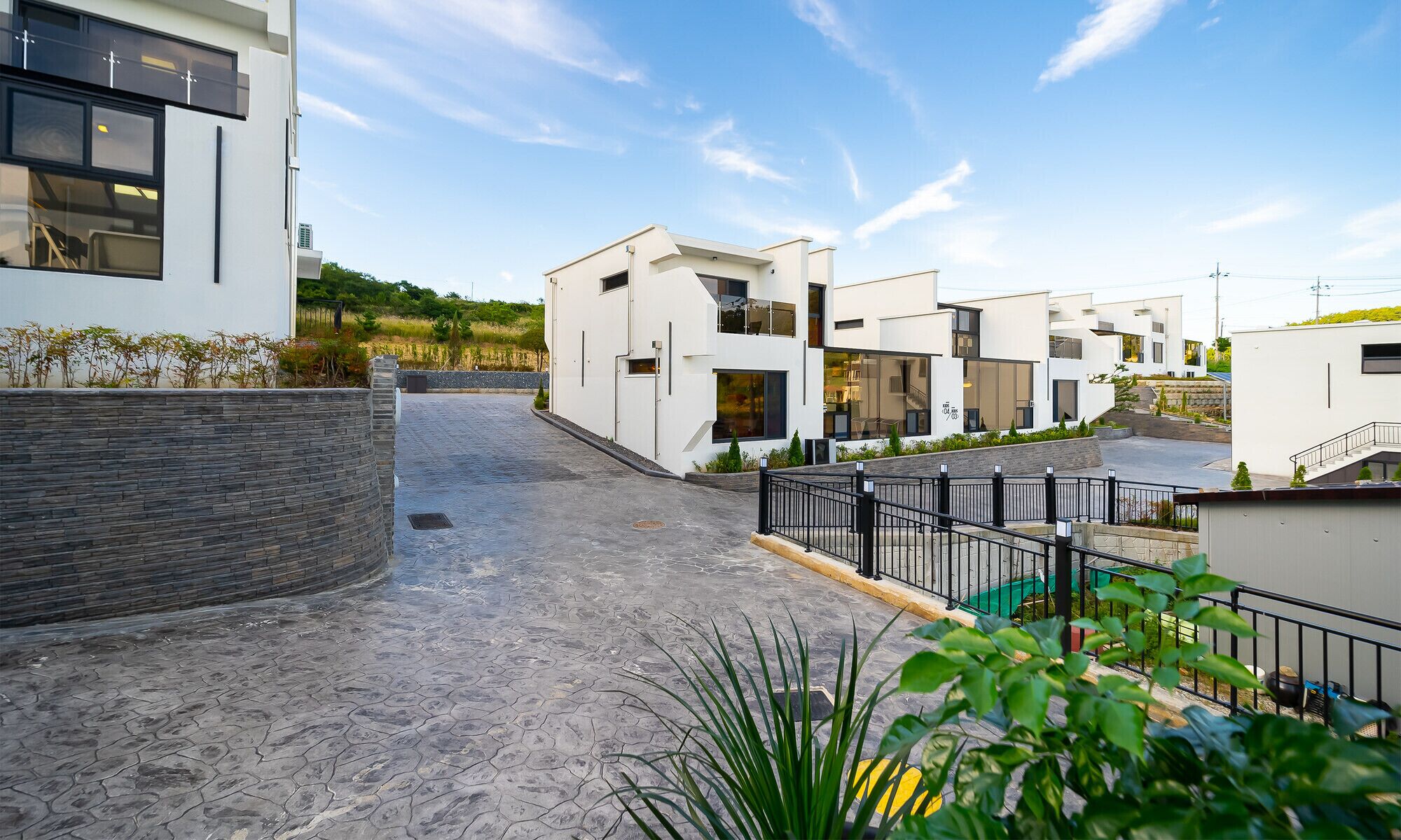 A modern residential area with contemporary architecture, paved pathways, and landscaped greenery.