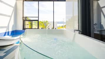 A modern bathroom with a glass-enclosed jacuzzi, a large window, and a view of the outdoors.