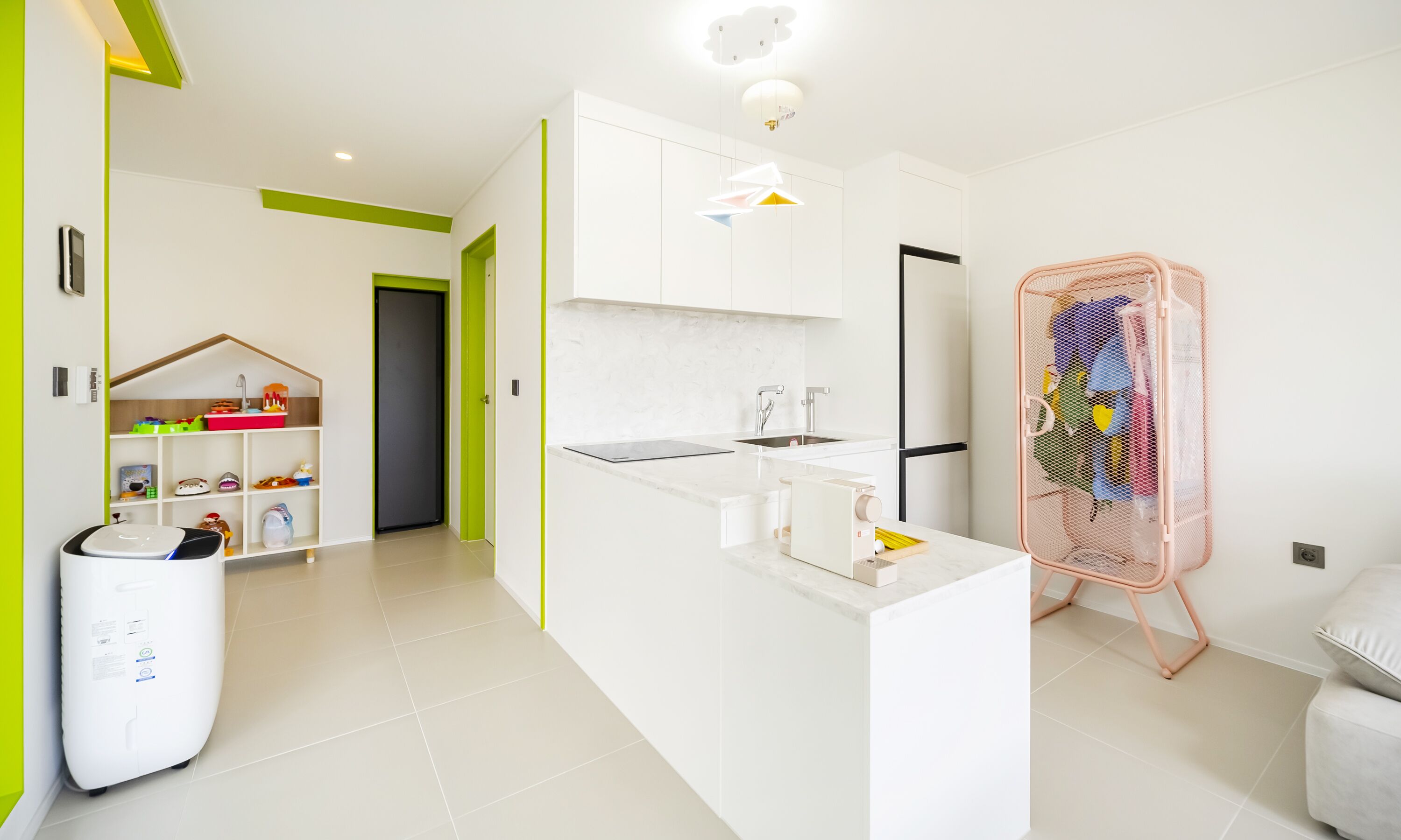 A modern kitchen with white cabinets, a central island, and a pink laundry basket.