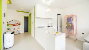 A modern kitchen with white cabinets, a central island, and a pink laundry basket.