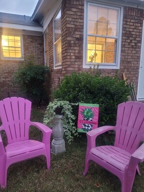 A house with two pink Adirondack chairs in the front yard, a welcome sign, and a brick exterior. - Byrd Nest @ Coventry · 3BR/2BA Home |Near Hospital, Downtown & US64/I-95 (Rocky Mount)