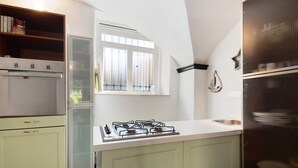 Une cuisine équipée d’une cuisinière à gaz, d’une fenêtre et d’un réfrigérateur.