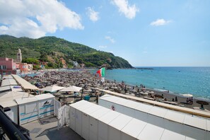 Ein Hotel direkt am Strand mit mehreren Zimmern, Blick auf das Meer und einem Bergpanorama im Hintergrund.