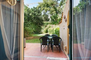 Un patio aperto con tavolo e sedie, un muro in pietra e vista su un giardino.