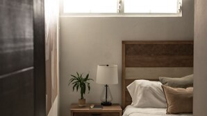 Une chambre à coucher avec un lit, une table de chevet, une lampe et une fenêtre.