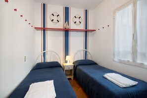 Ein Zimmer mit zwei Betten, einem Nachttisch und einem Fenster mit Vorhängen.