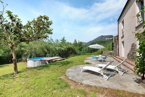 A backyard with a swimming pool, lounge chairs, and a stone patio. - Villa 'Nespolo' with Mountain View, Private Pool and Wi-Fi (Levanto)