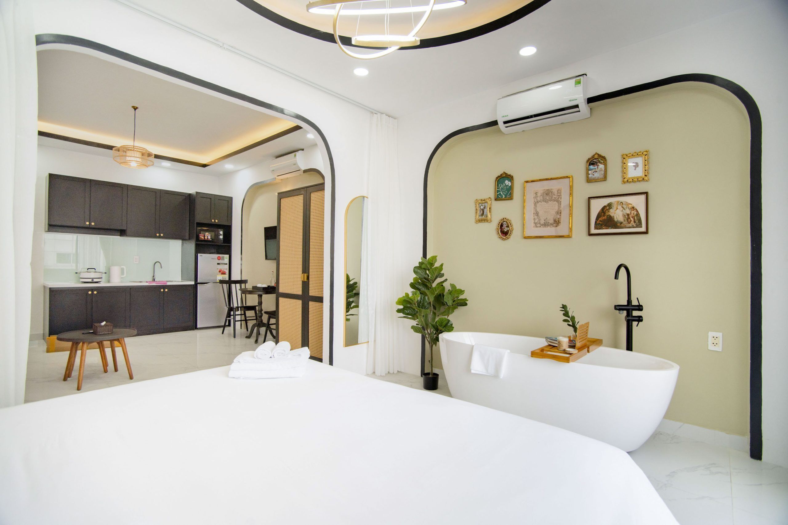 Una habitación de hotel moderna con una cama grande, una bañera, una cocina y un comedor.