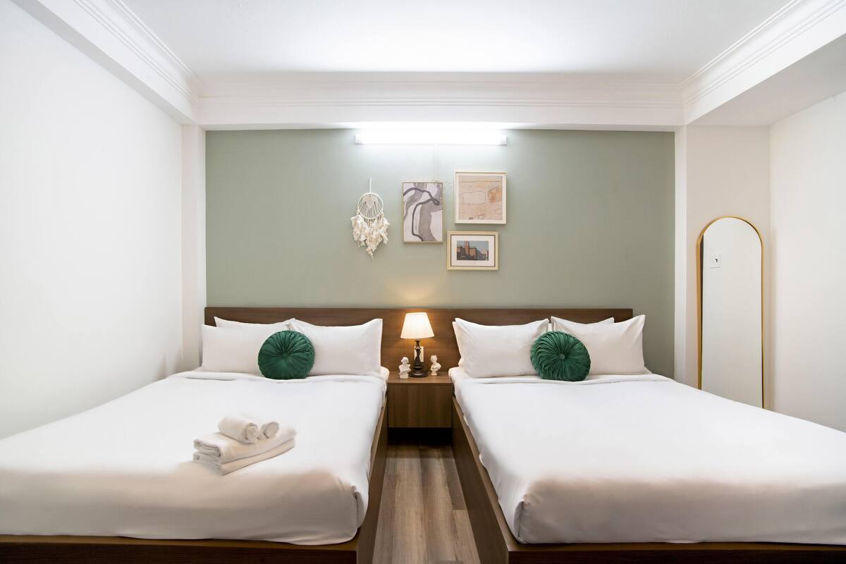 Ein Hotelzimmer mit zwei Betten, einem Nachttisch mit Lampe und Wandbildern.