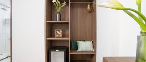 Un baño moderno con cabina de ducha de vidrio, tocador de madera y unidad de almacenamiento empotrada con estantes y un refrigerador pequeño.