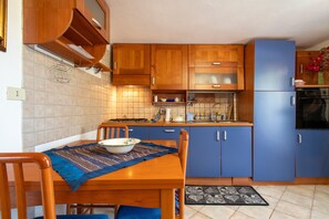 A kitchen with wooden cabinets, a blue refrigerator, and a dining table with chairs.