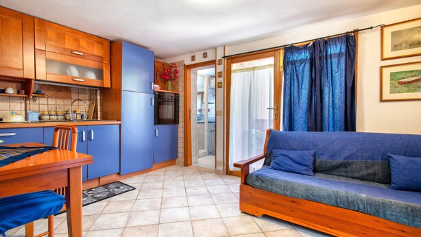 A compact living space with a kitchenette, dining area, and a sofa. - Holiday Home 'Casetta Brandinu' with Mountain View, Balcony & Wi-Fi (Sassari)