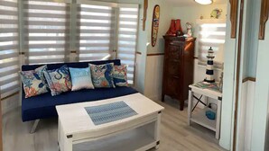 Um quarto aconchegante com um sofá azul, uma mesa pequena e um ventilador de teto.