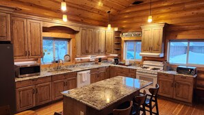 Una cocina amplia con armarios de madera, encimeras de granito, una isla central y vistas a la Calle Principal.