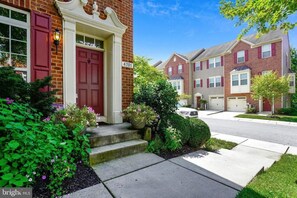 A residential street with a row of townhouses, each with a red door and a number plaque. - Sunny Townhome/4Br/2.5Bath (Ellicott City)