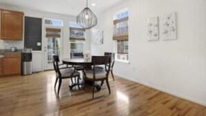 Una cocina moderna con armarios de madera, una mesa de comedor con sillas e iluminación colgante.