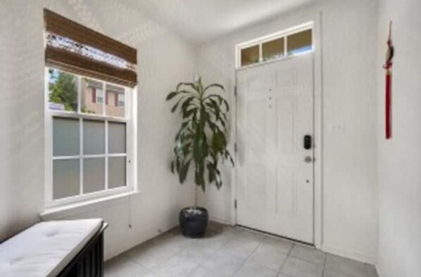 A room with a large window, a potted plant, and a closed door. - Sunny Townhome/4Br/2.5Bath (Ellicott City)