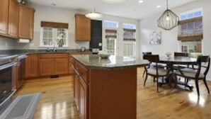Una cocina moderna con armarios de madera, una isla grande y un comedor con sillas.