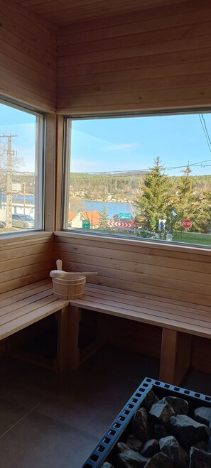 A wooden sauna room with a bench and a wooden bucket. - Apartment with panoramic lake view, sauna, close to hiking trails. (Orfu)