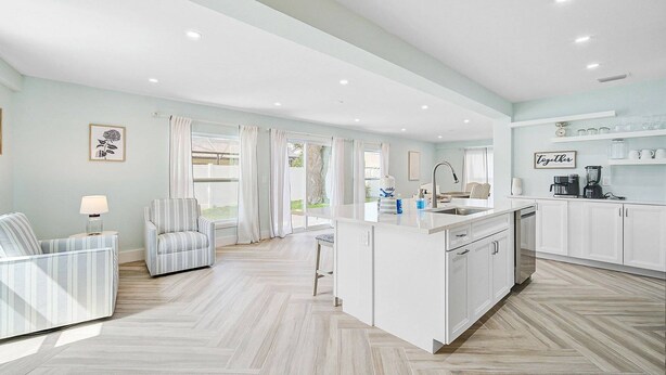 A spacious kitchen with a central island, white cabinetry, and a view to the outside. - Private Pool Retreat Near Anna Maria Island -Spa - Optional Pool Chiller-EV Charger (Bradenton)
