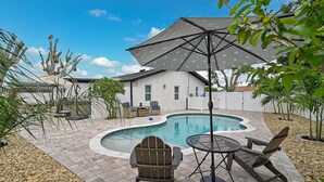 A backyard with a swimming pool, patio furniture, and a covered seating area. - Private Pool Retreat Near Anna Maria Island -Spa - Optional Pool Chiller-EV Charger (Bradenton)