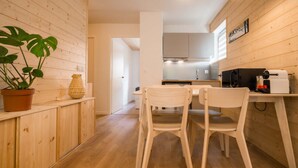 Une cuisine de taille réduite avec des meubles en bois, une table à manger avec des chaises et une plante en pot.