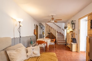 A cozy living room with a sofa, a small table, a ceiling fan, and a staircase leading to another level.
