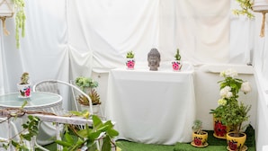 A small, enclosed outdoor area with a round table, chairs, and various potted plants. - COZY HOME CUSCO (Cusco)
