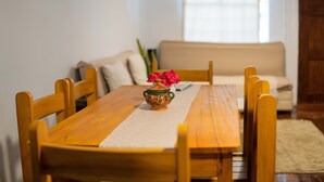 A wooden dining table with a vase of flowers, surrounded by wooden chairs. - COZY HOME CUSCO (Cusco)