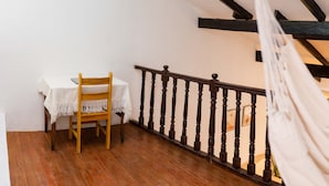 A room with a wooden floor, a white table with a chair, a hammock, and a black balustrade. - COZY HOME CUSCO (Cusco)