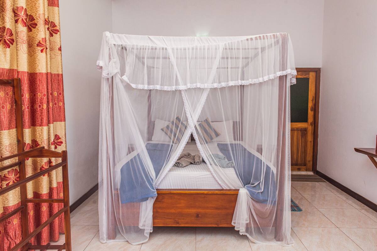 A single bed with a white canopy, a wooden headboard, and a blue bedspread.