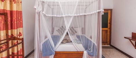 A single bed with a white canopy, a wooden headboard, and a blue bedspread.