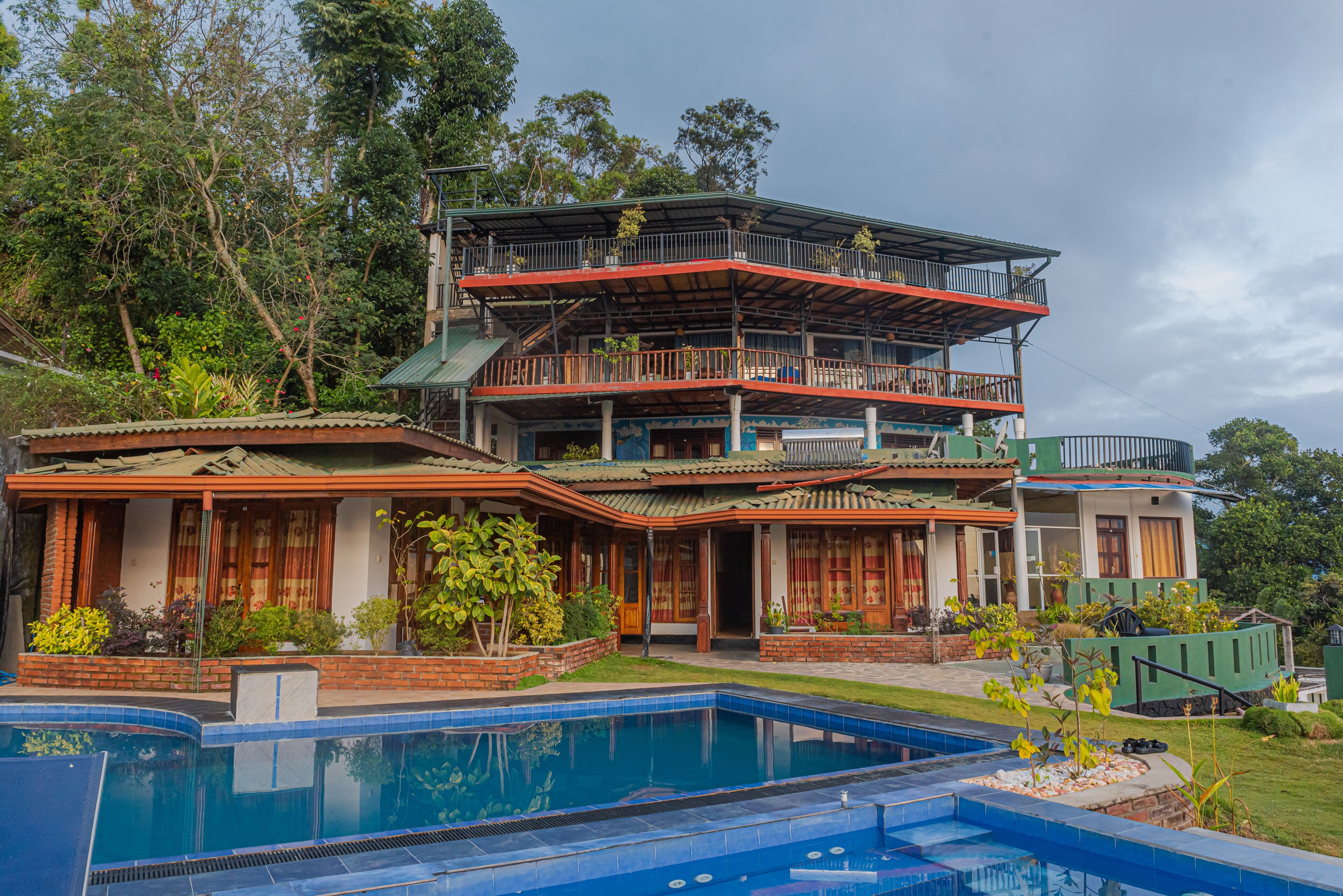 A multi-story house with a swimming pool in front.