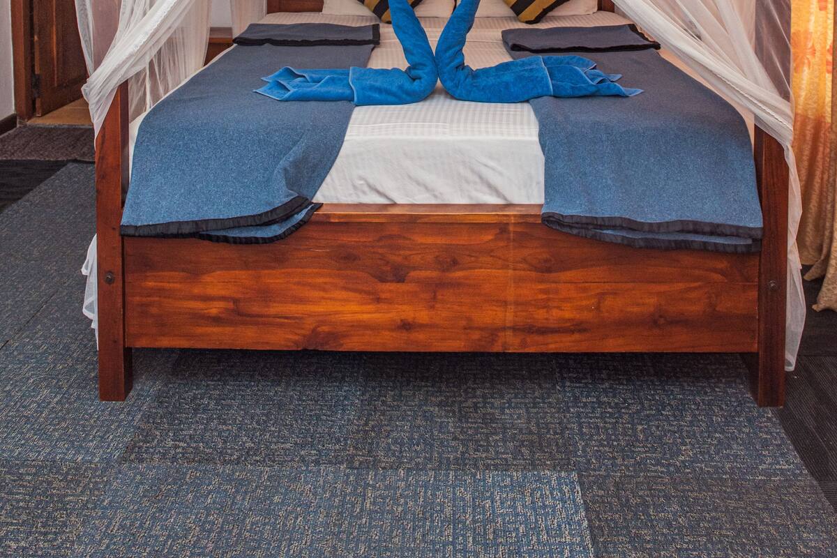 A bed with a canopy, pillows, and a blanket.
