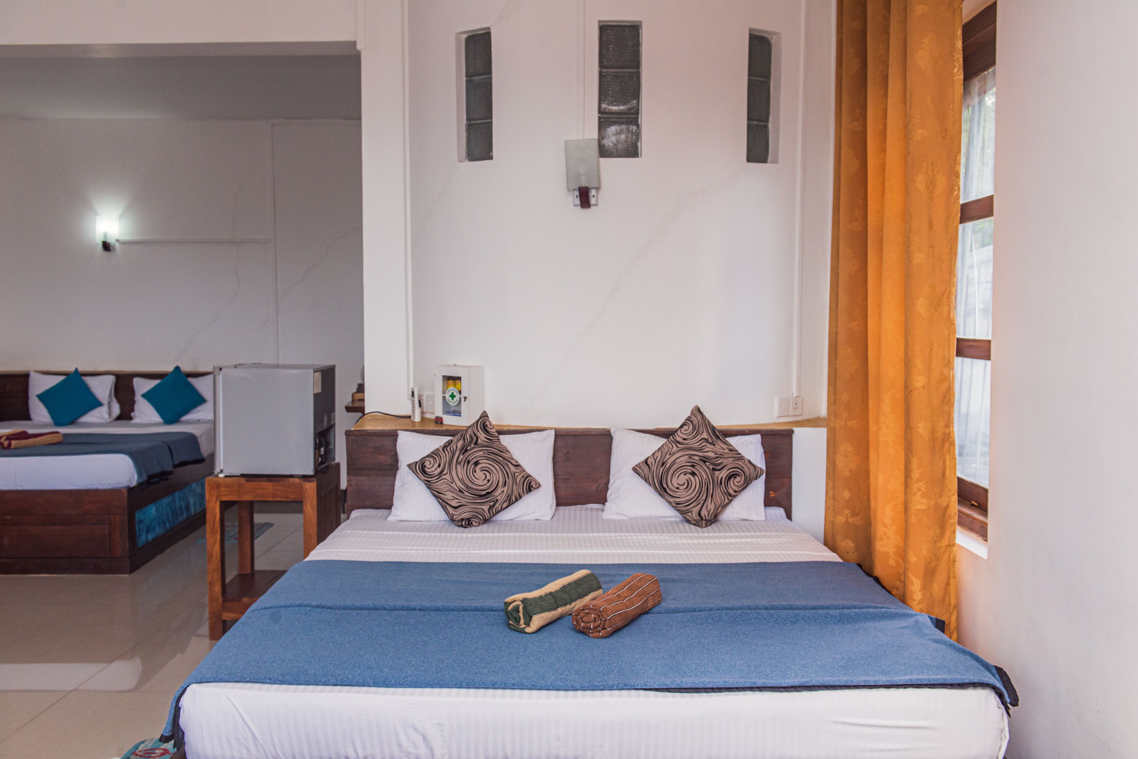 Una habitación de hotel con una cama, una mesita de noche, una lámpara y una ventana con cortinas.
